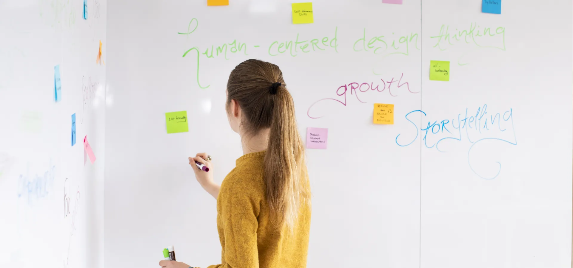A student stands at a white board, writing.