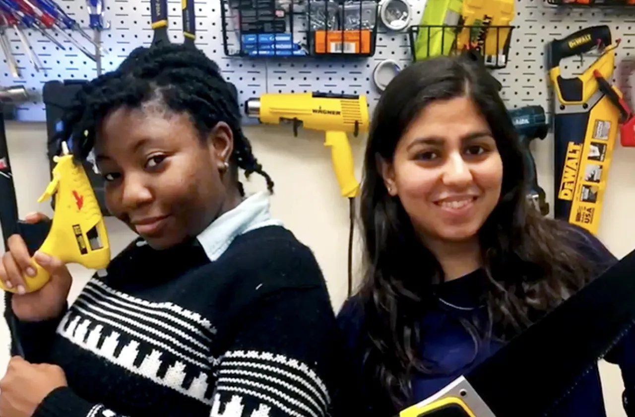 Two students holding tools in class