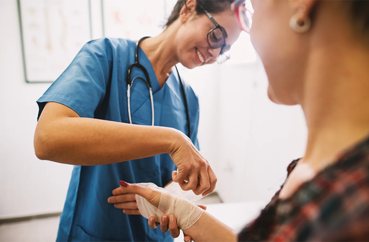 Doctor bandaging an injury to a woman's wrist