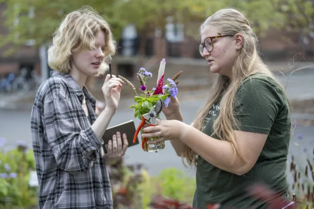 two white, blonde female students examining a bouquet of flowers