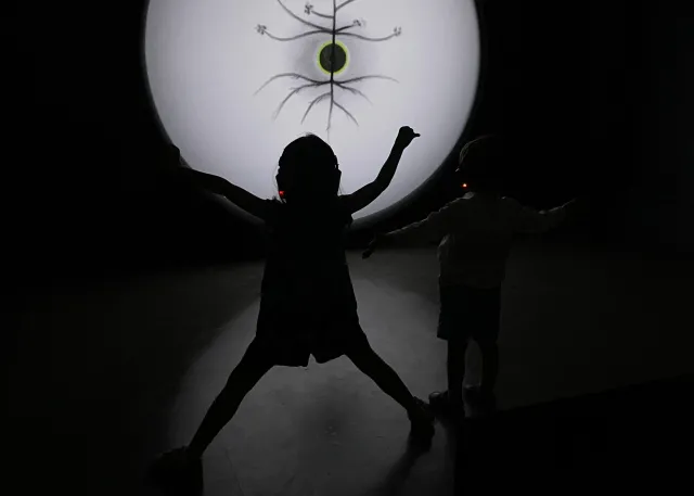 silhouette for a 4 your old in front of a video installation in a dark room