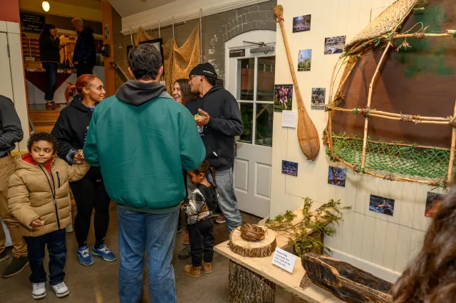 People standing in a gallery with a mini wetu.