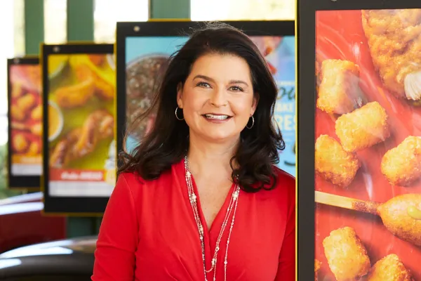 Claudia San Pedro smiling by the menus at a Sonic restaurant