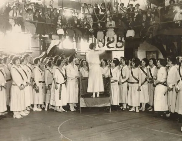 Students in white dresses singing.