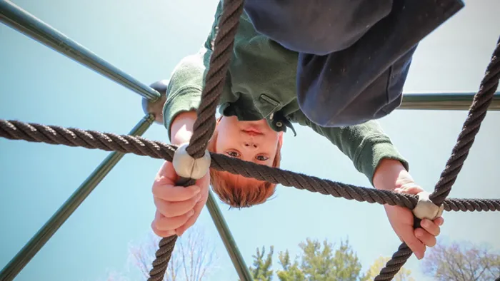 child upside down on jungle gym