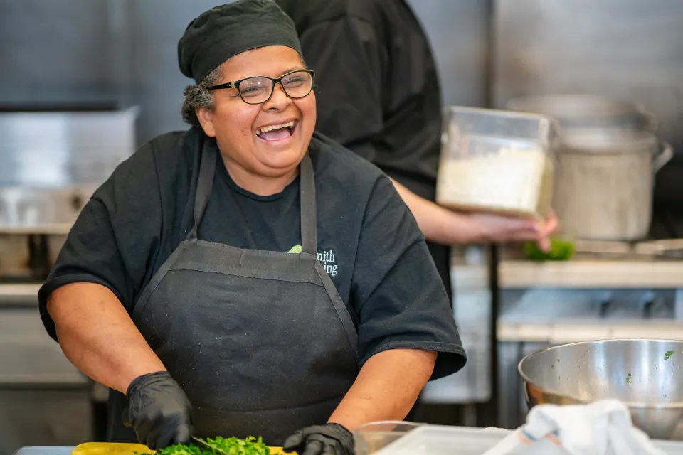 Maria Aguilar smilies while chopping vegetables in the Chase-Duckett kitchen