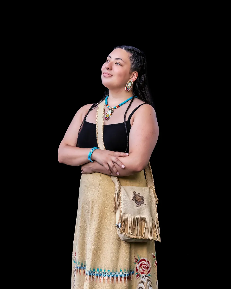 portrait of a woman standing in front of a black background with a black shirt and a tan skirt