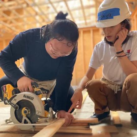 Two students using a skill saw.